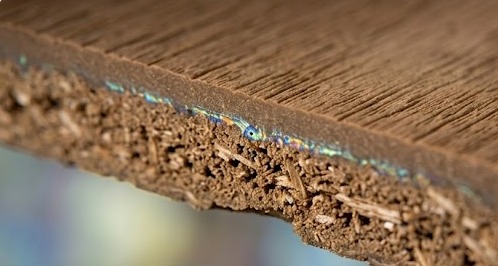 Macro view of co-extruded WPC decking showing the dense capping layer molecularly bonded to the core